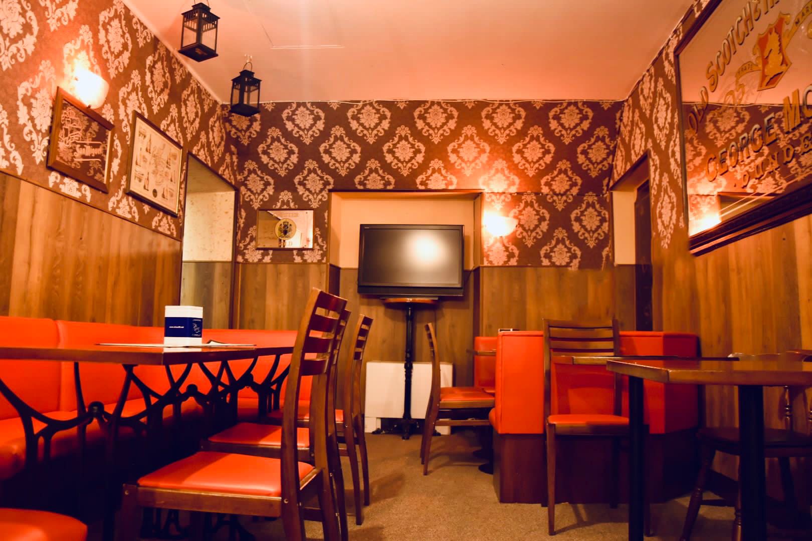 Sala interna del The Bull Pub Torino con divanetti rossi e carta da parati damascata